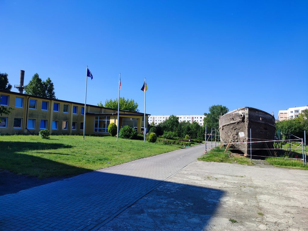 Außengelände mit Parkfläche und Fahnenmasten